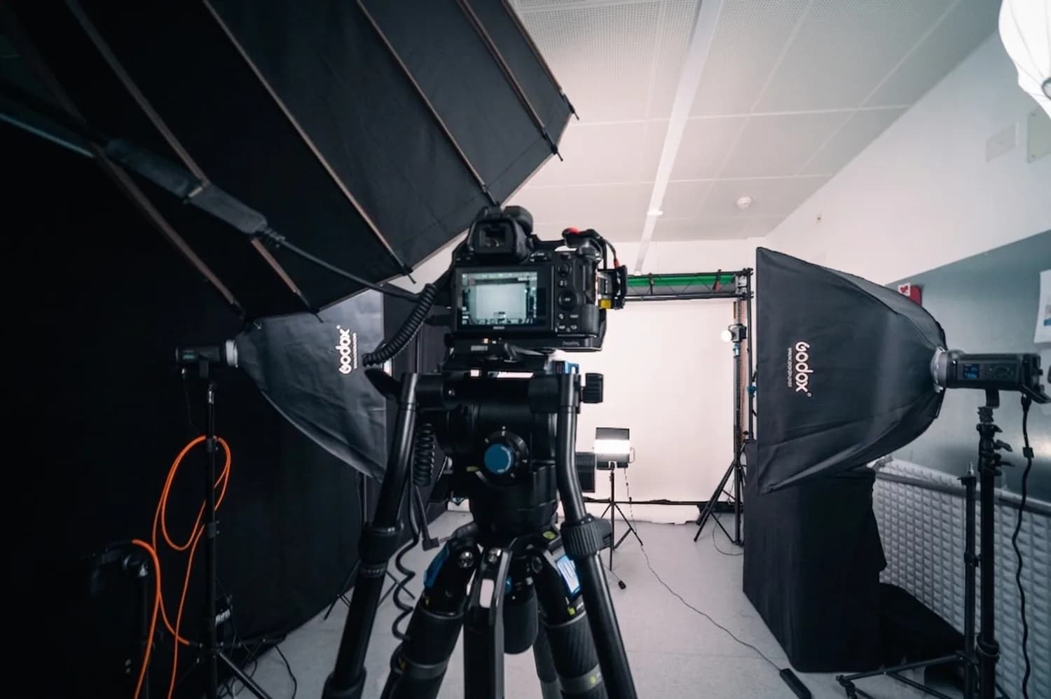 Le studio de Marly éclairé pour un tournage : caméra sur pied, boîtes à lumière et fond blanc