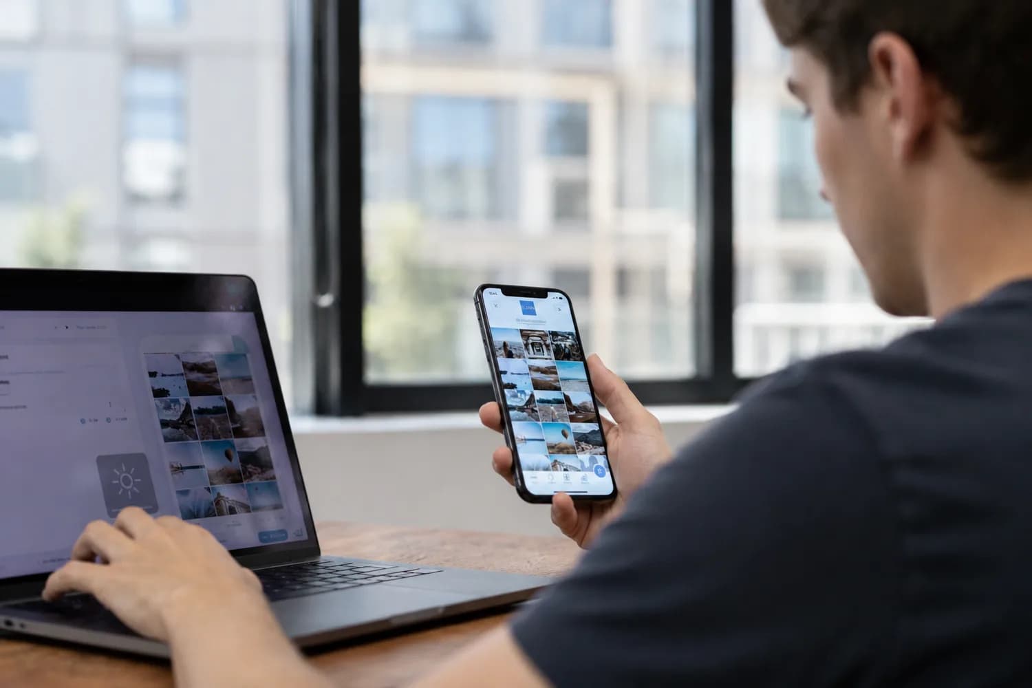 Une personne trie des photos sur son téléphone à côté de son ordinateur portable